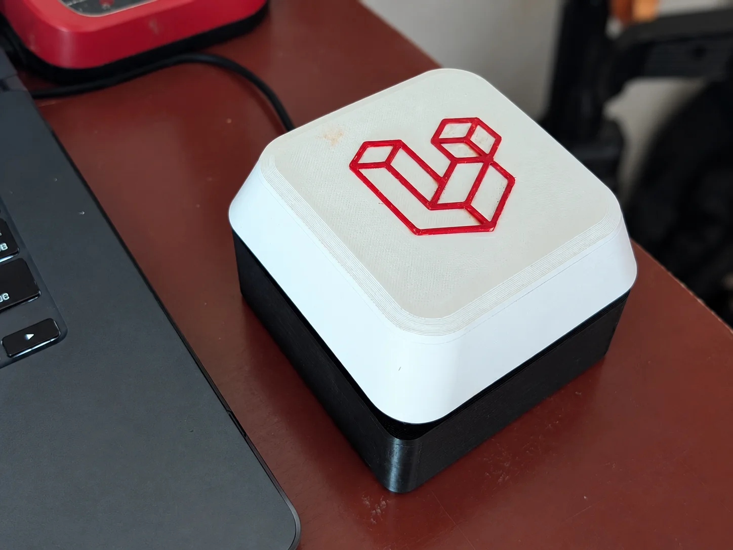 Finished white and black oversized Laravel macro button beside a laptop